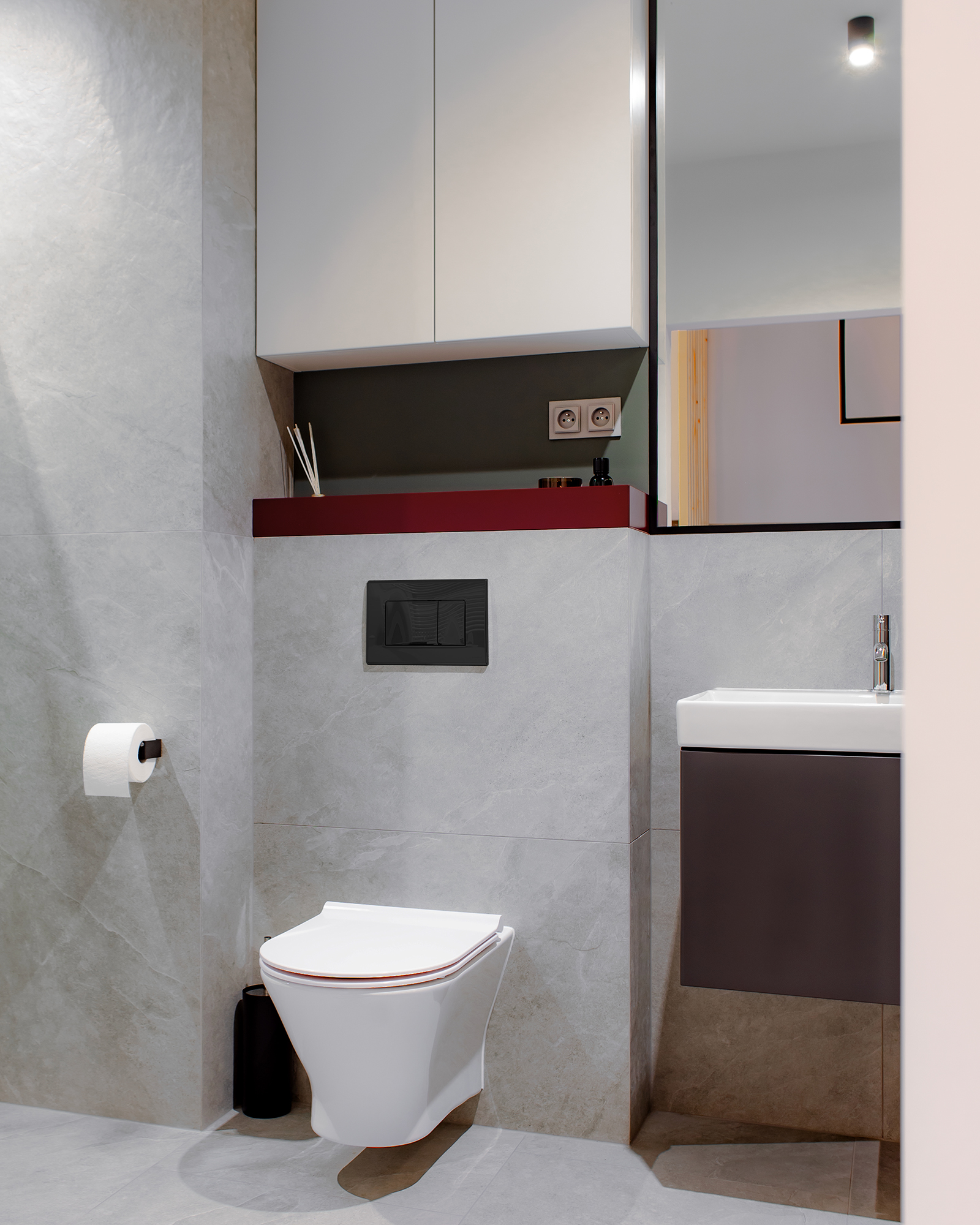 Choć króluje tu szarość i złamana biel, to pojawia się także zgaszona zieleń na ścianach, podkreślona półeczką w głębokiej czerwieni.